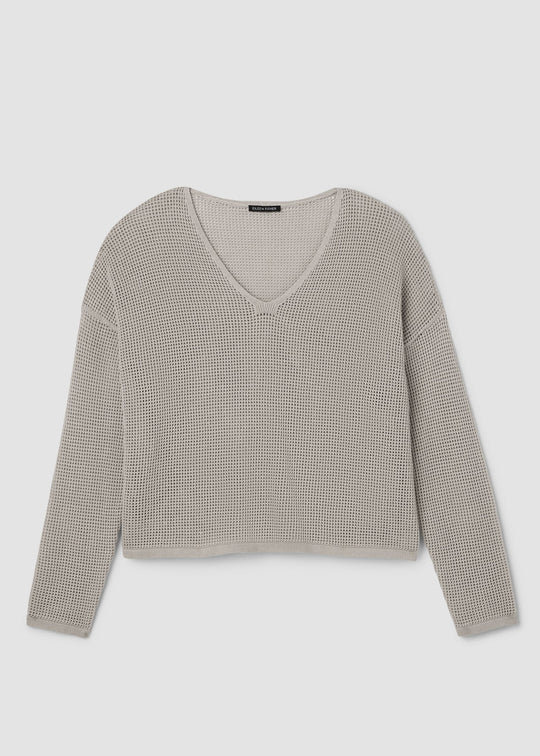 A cropped, long-sleeve knit sweater with a V-neckline, featuring a fine micro-check pattern in beige and gray, displayed on a neutral light gray background.
