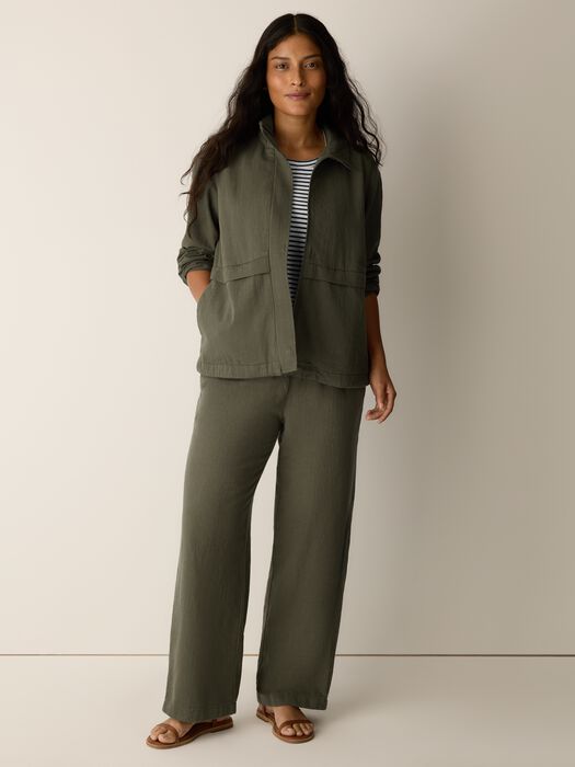 Olive zip-up jacket with stand collar over striped top, long sleeves and pockets
