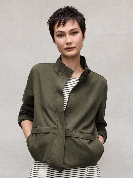 Olive zip-up jacket close-up with stand collar, flap pockets, and striped layer