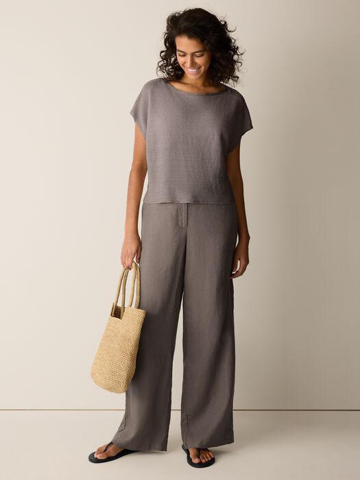 Wide-leg linen trousers in taupe gray worn with matching top and woven bag