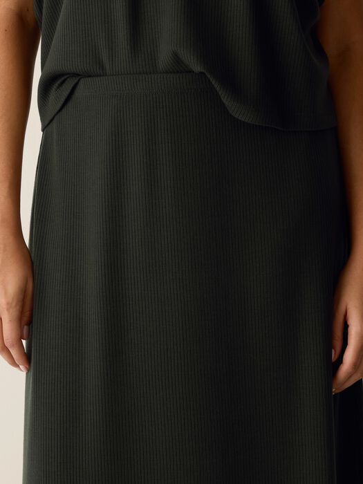 Black ribbed knit skirt close-up, vertical rib texture and waistband seam