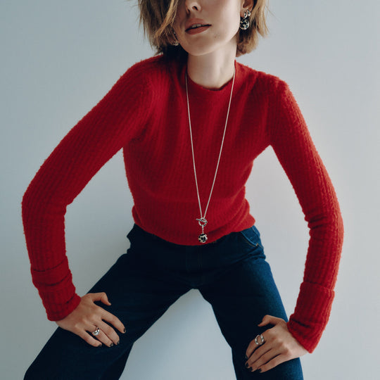 Silver pendant necklace with circular charm worn by model in red sweater