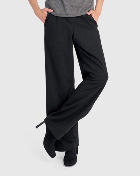 Wide-leg black pull-on trousers with side pockets, worn with black ankle boots, side view