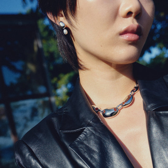 Pearl drop earrings with silver hardware worn by model in black leather jacket