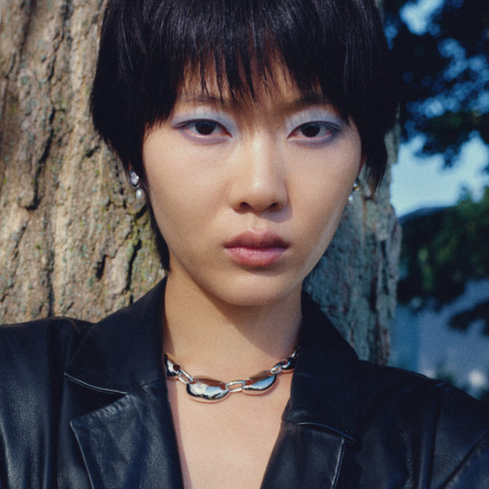 Silver pearl drop earrings worn by model with short dark hair