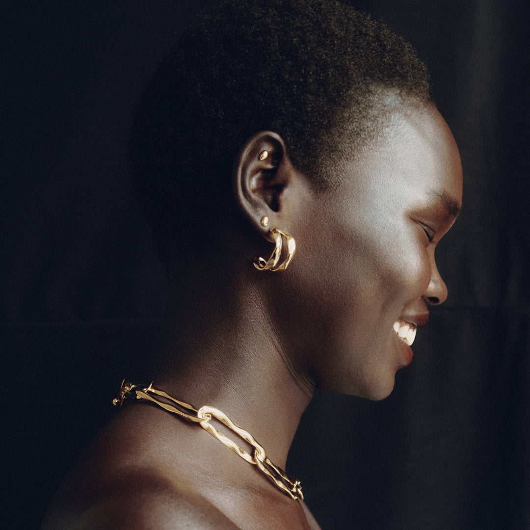 Gold hoop earrings worn by model in profile, showing curved design