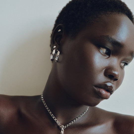 Silver hoop earrings worn by model with matching chain necklace, profile view