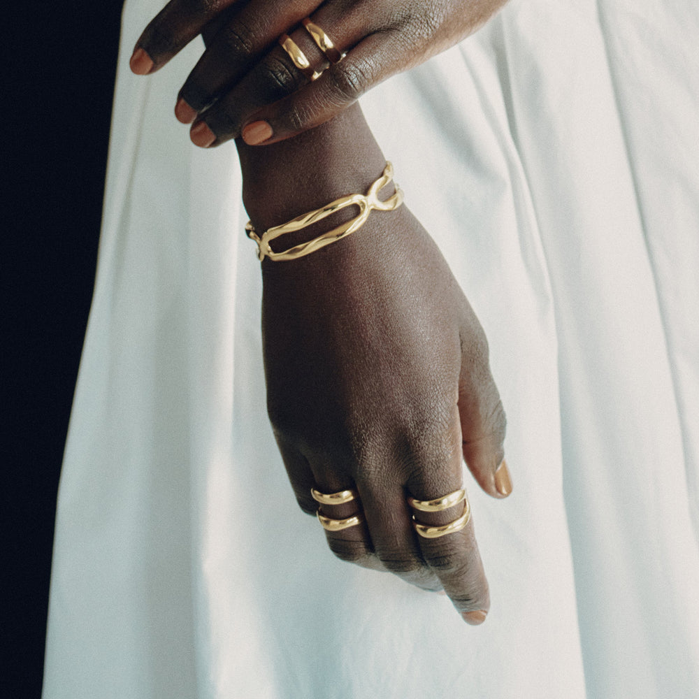 Gold rings worn on fingers with hook-shaped design detail visible on model's hands