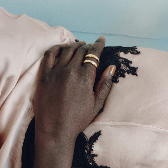 Gold ring worn on finger with black lace trim garment in soft lighting