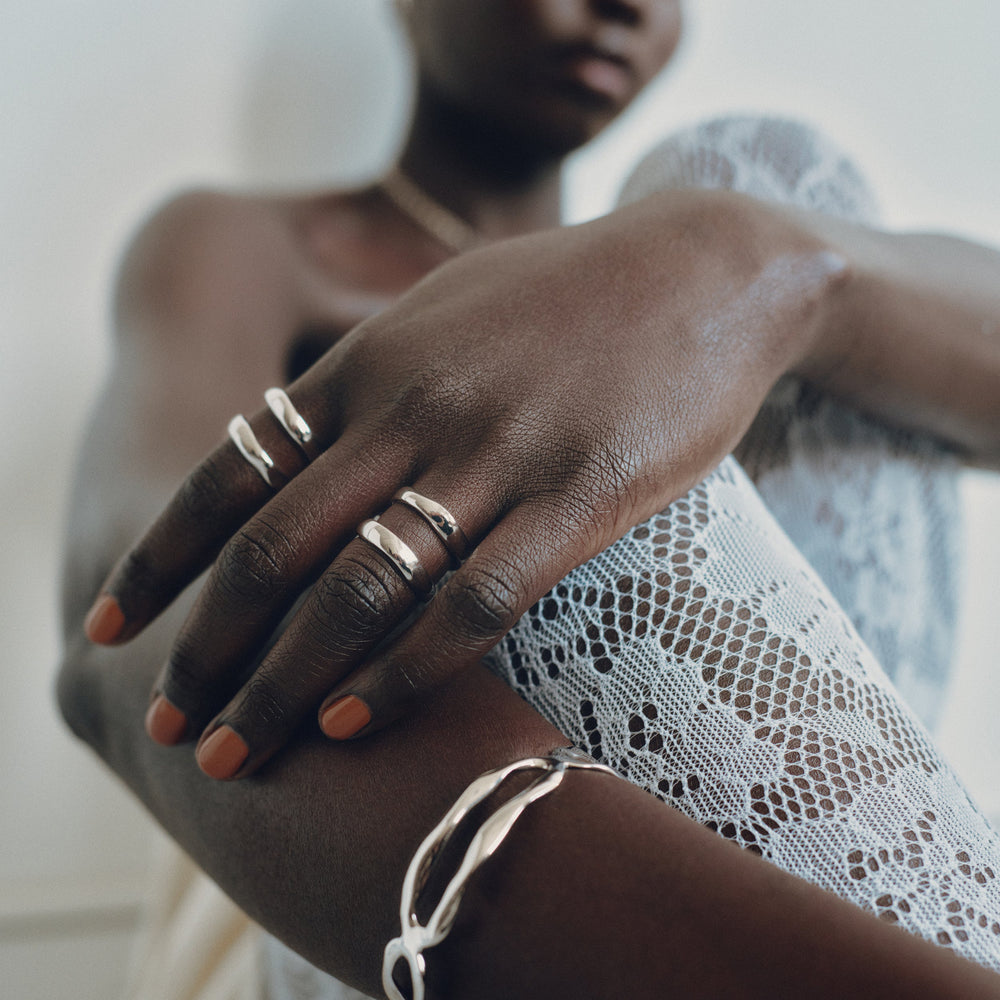 Silver rings worn on fingers, multiple thin bands stacked together on hand