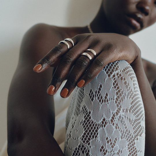 Silver rings worn on fingers, hand resting on white lace fabric