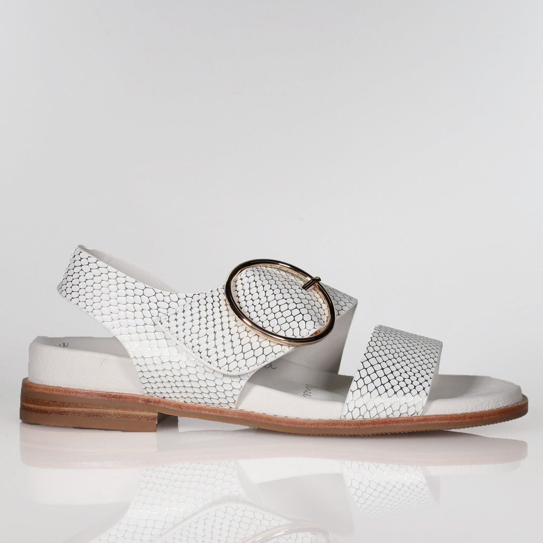 White leather sandal with metallic embossed pattern, oval buckle, flat sole, side view