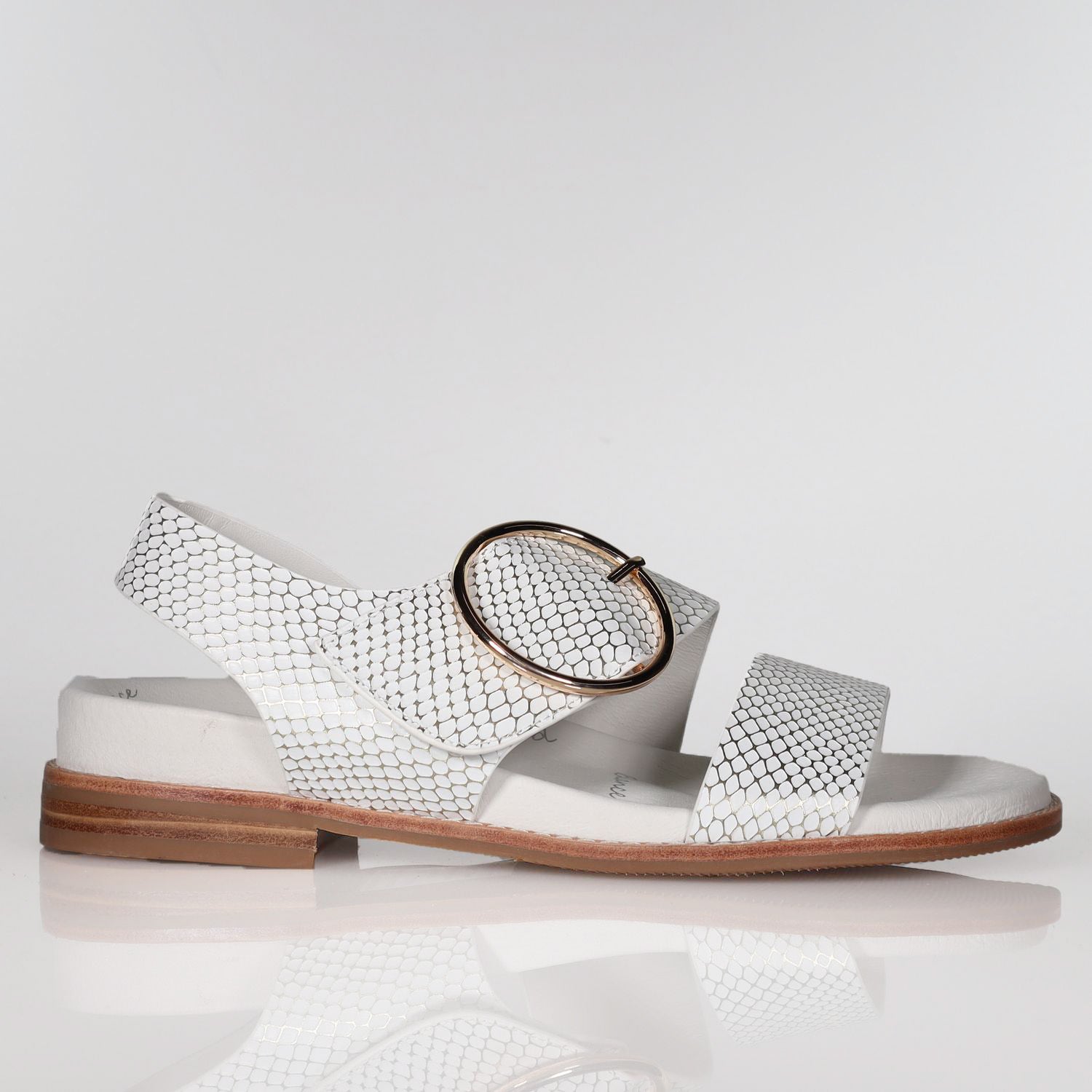 White leather sandal with metallic embossed pattern, oval buckle, flat sole, side view