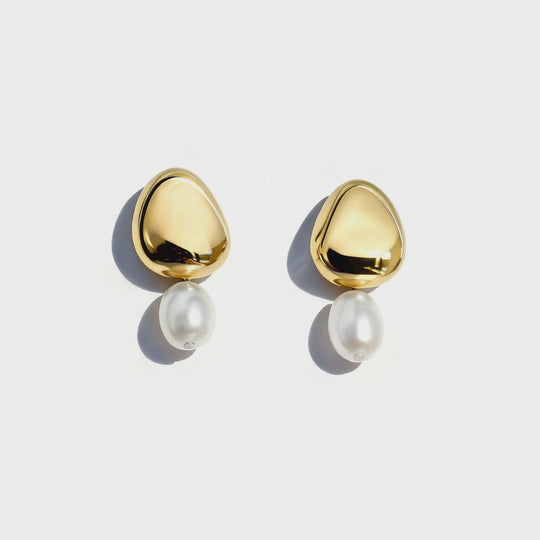 Gold teardrop-shaped earrings with white pearl drops displayed on white background