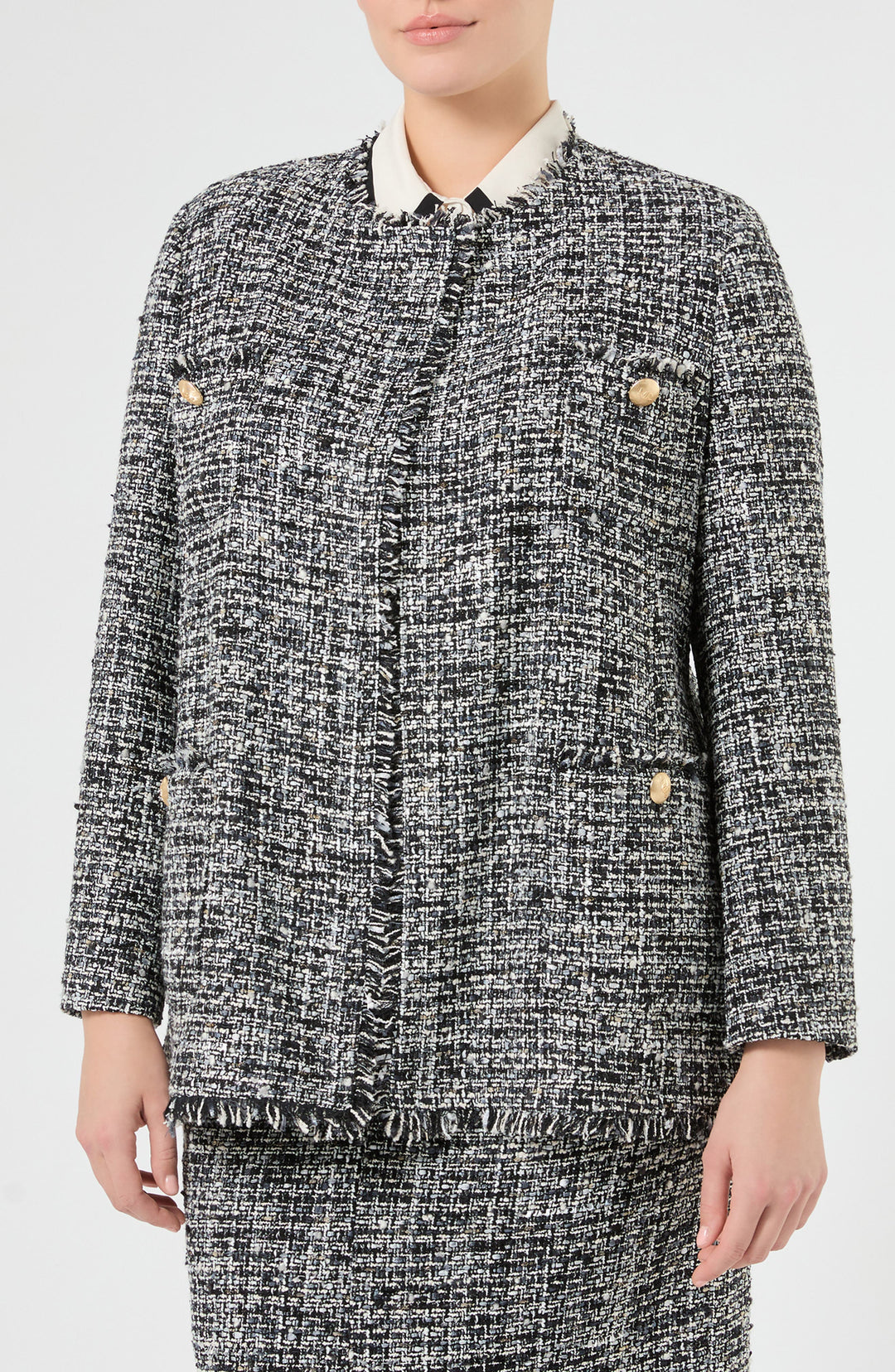 Black and white tweed boucle jacket with fringe trim, gold buttons, and collarless neckline, front view on model