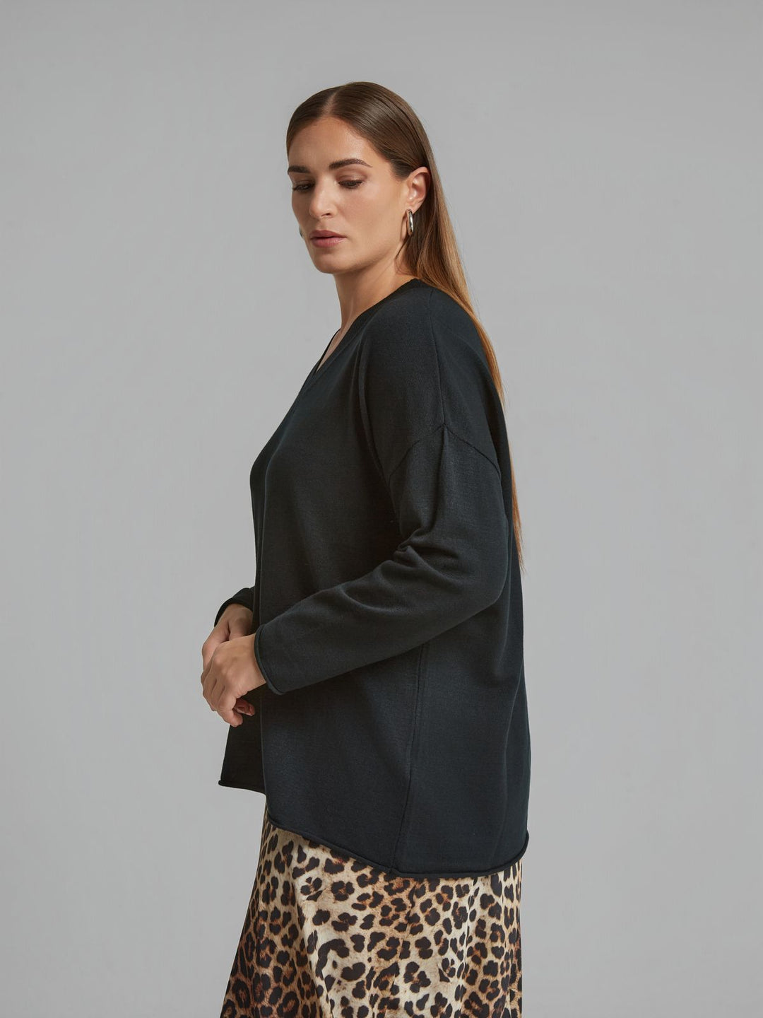 Black V-neck sweater with roll hem and long sleeves, side view