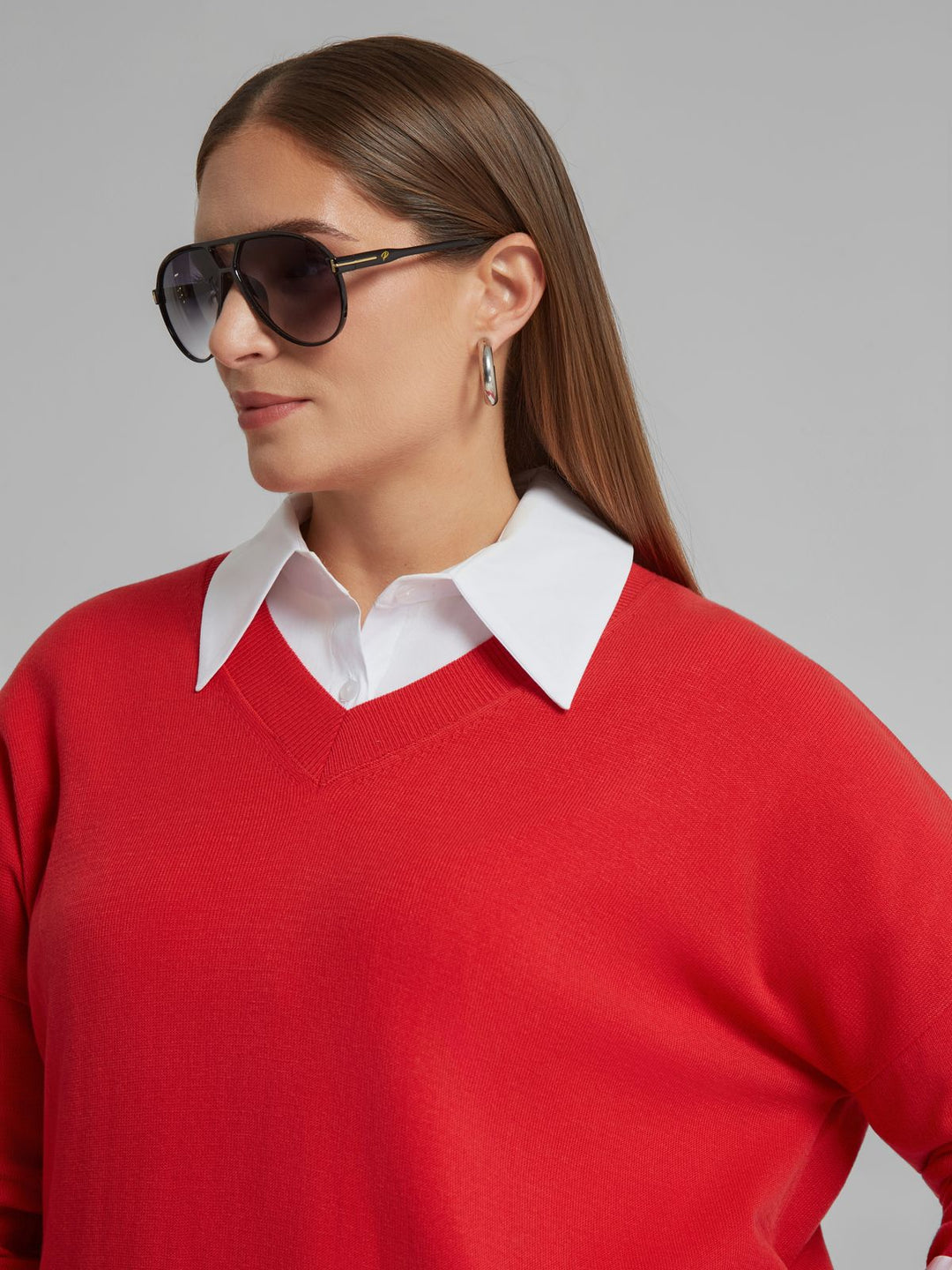 Red V-neck sweater worn over a white collared shirt, long sleeves