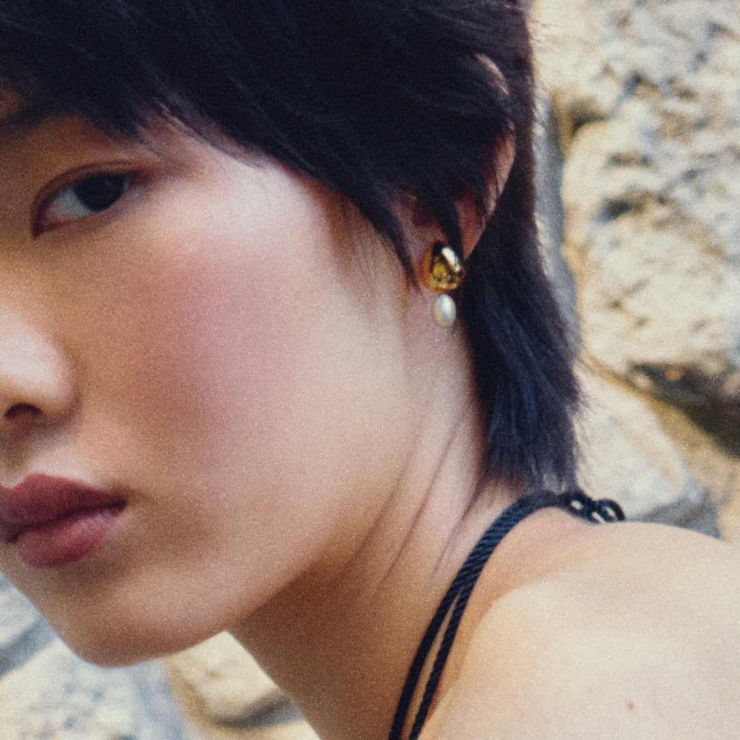 Gold drop earrings with white pearl dangles worn by model with dark hair