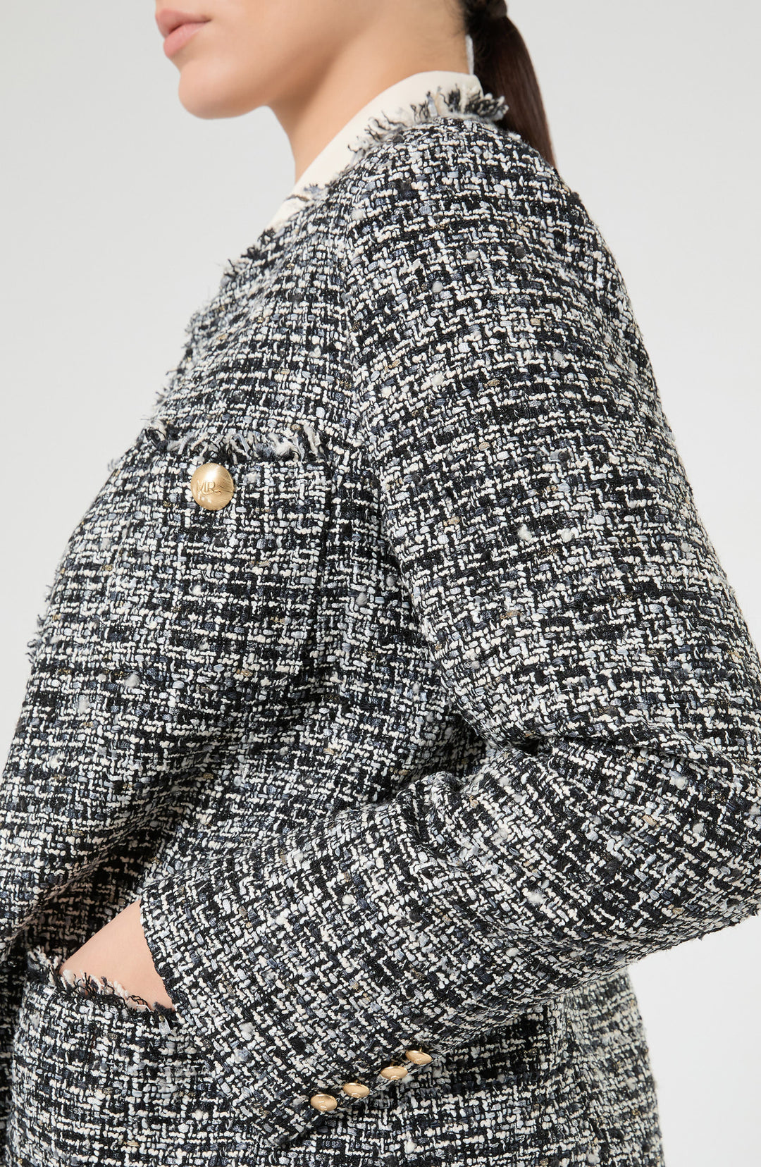 Close-up side view of tweed boucle jacket with gold buttons and frayed trim details