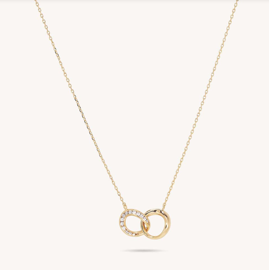 Gold necklace with two interlocked circles, one set with sparkling white stones, on delicate chain