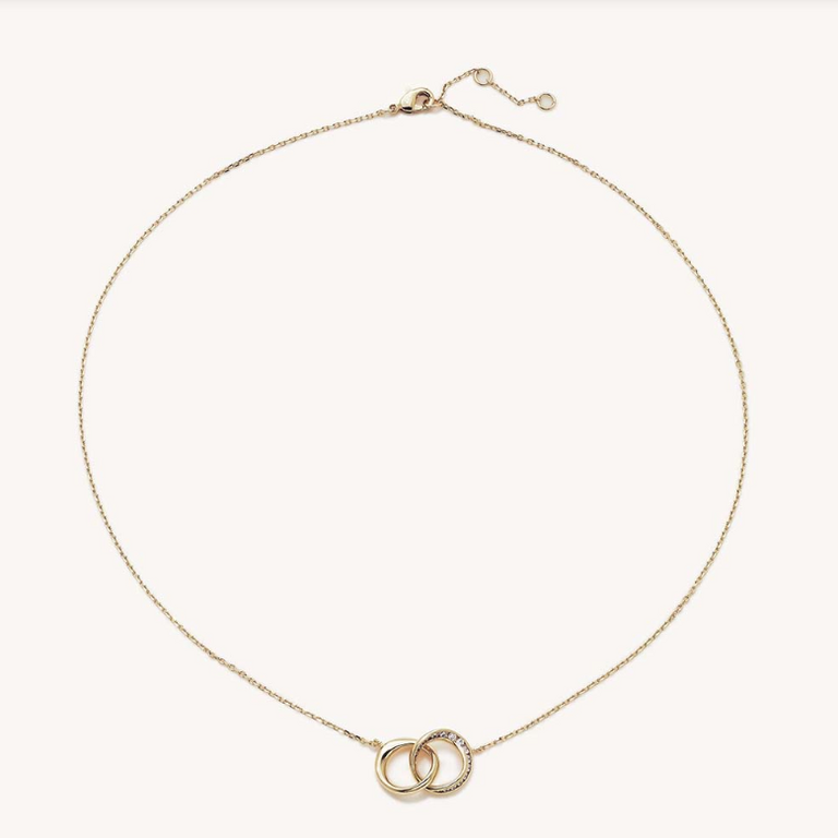 Delicate gold chain necklace with two interlocking rings, one accented with sparkling clear stones