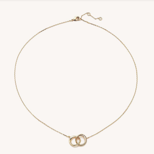 Delicate gold chain necklace with two interlocking rings, one accented with sparkling clear stones