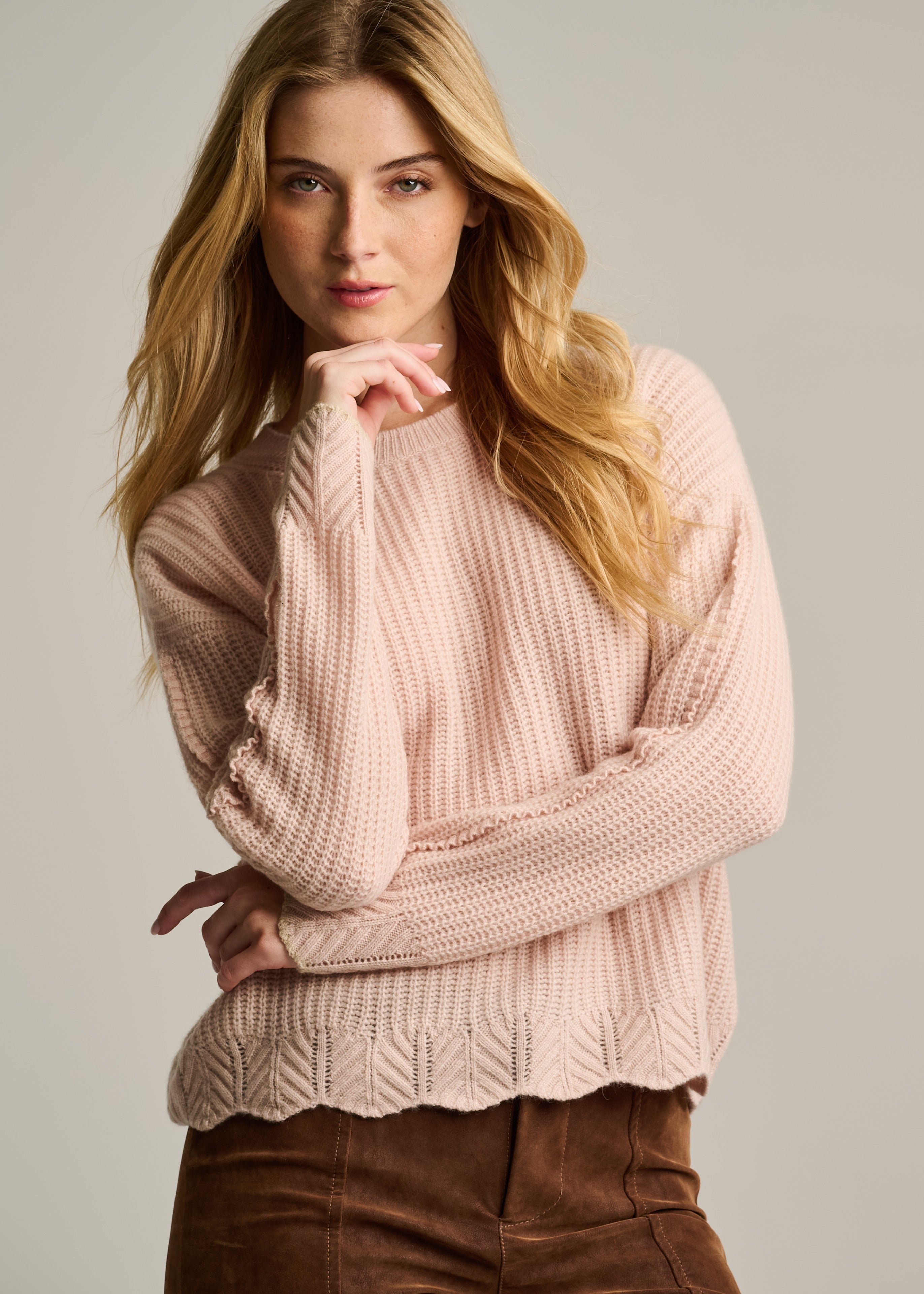 Woman wearing a pink sweater against a plain background