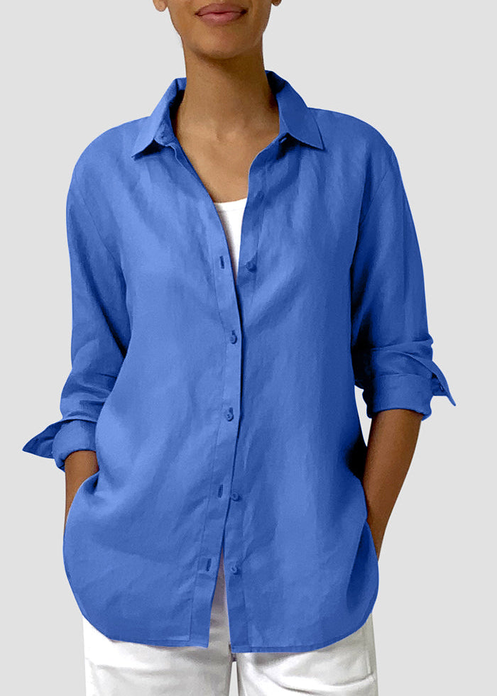 Person wearing a blue button-up shirt with rolled-up sleeves on a light gray background