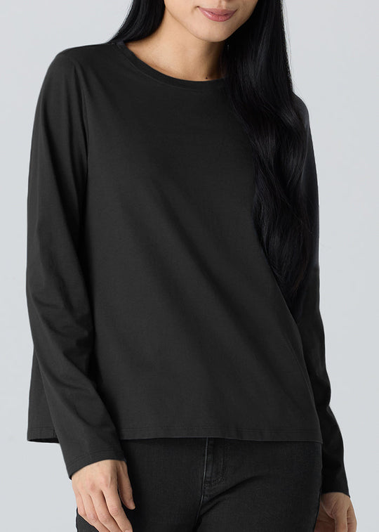 Person wearing a black long-sleeve top and black pants on a light gray background