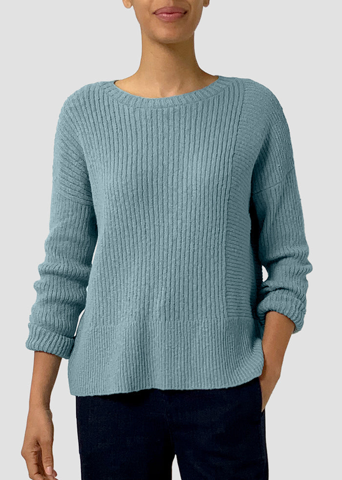 Person wearing a light blue sweater on a plain background