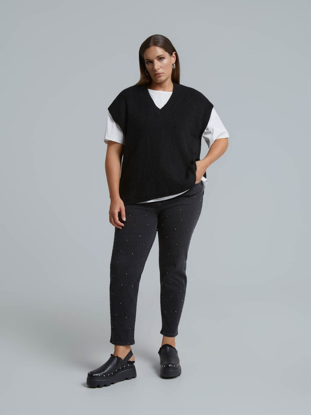 Black V-neck knit sweater vest layered over white t-shirt, front view on model
